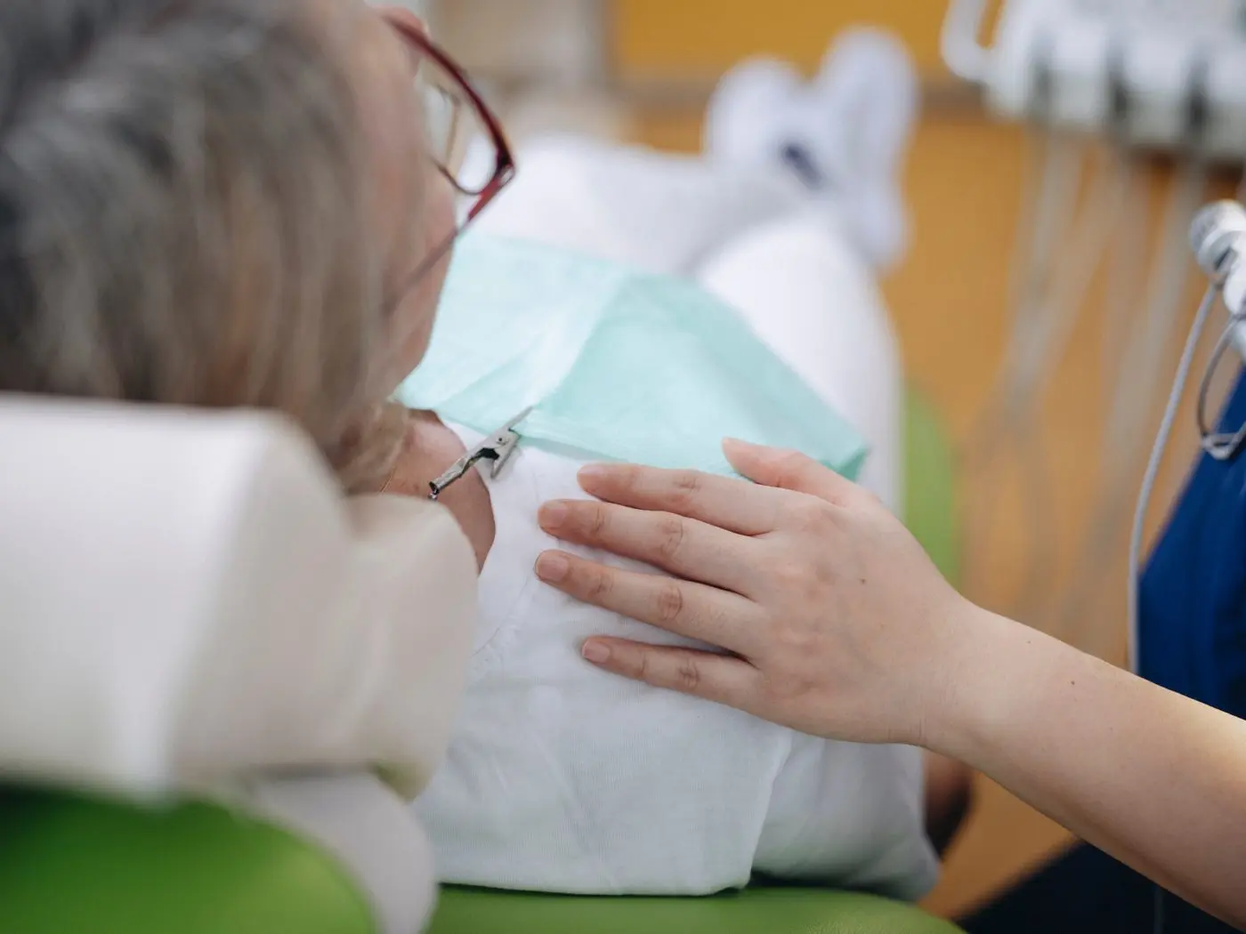 Die Hand der Behandlerin liegt beruhigend auf dem Arm der Patientin