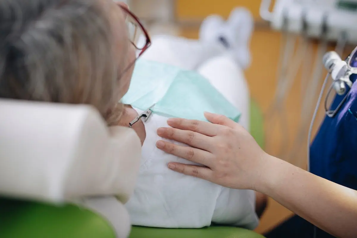 Die Hand der Behandlerin liegt beruhigend auf dem Arm der Patientin