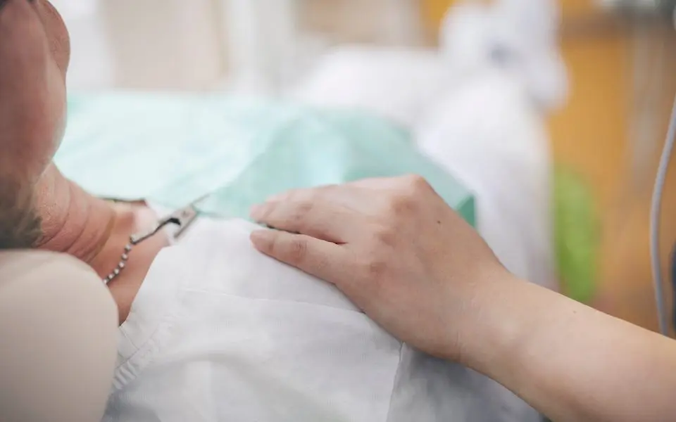 Ruhige Behandlung, die Hand der Behandlerin liegt auf dem Arm der Patientin
