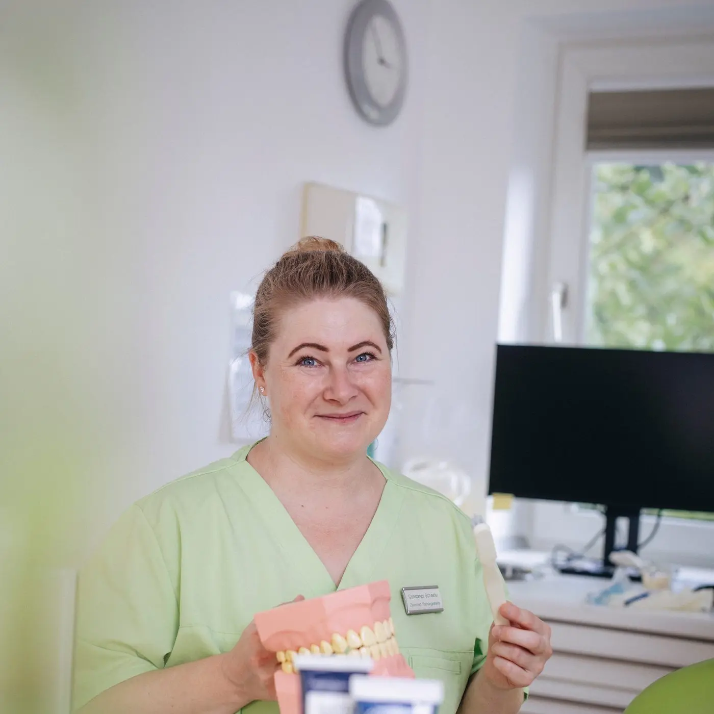 Mitarbeiterin erklärt die Zahnreinigung an einem Kiefermodell